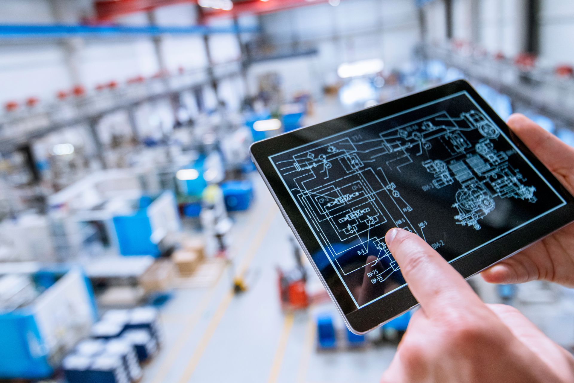 a photo of a hand holding a tablet device in a factory